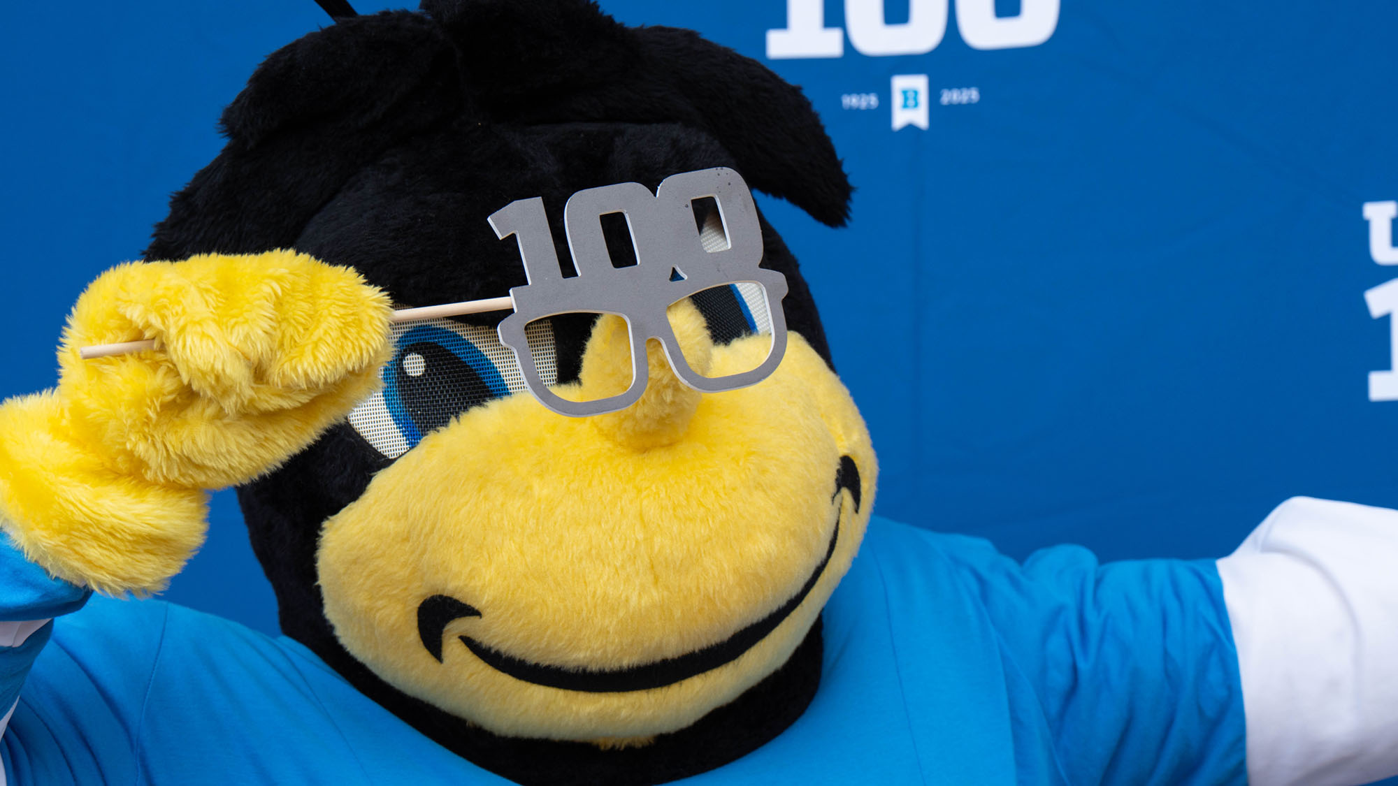 Eubie the bee mascot poses with a photo booth prop