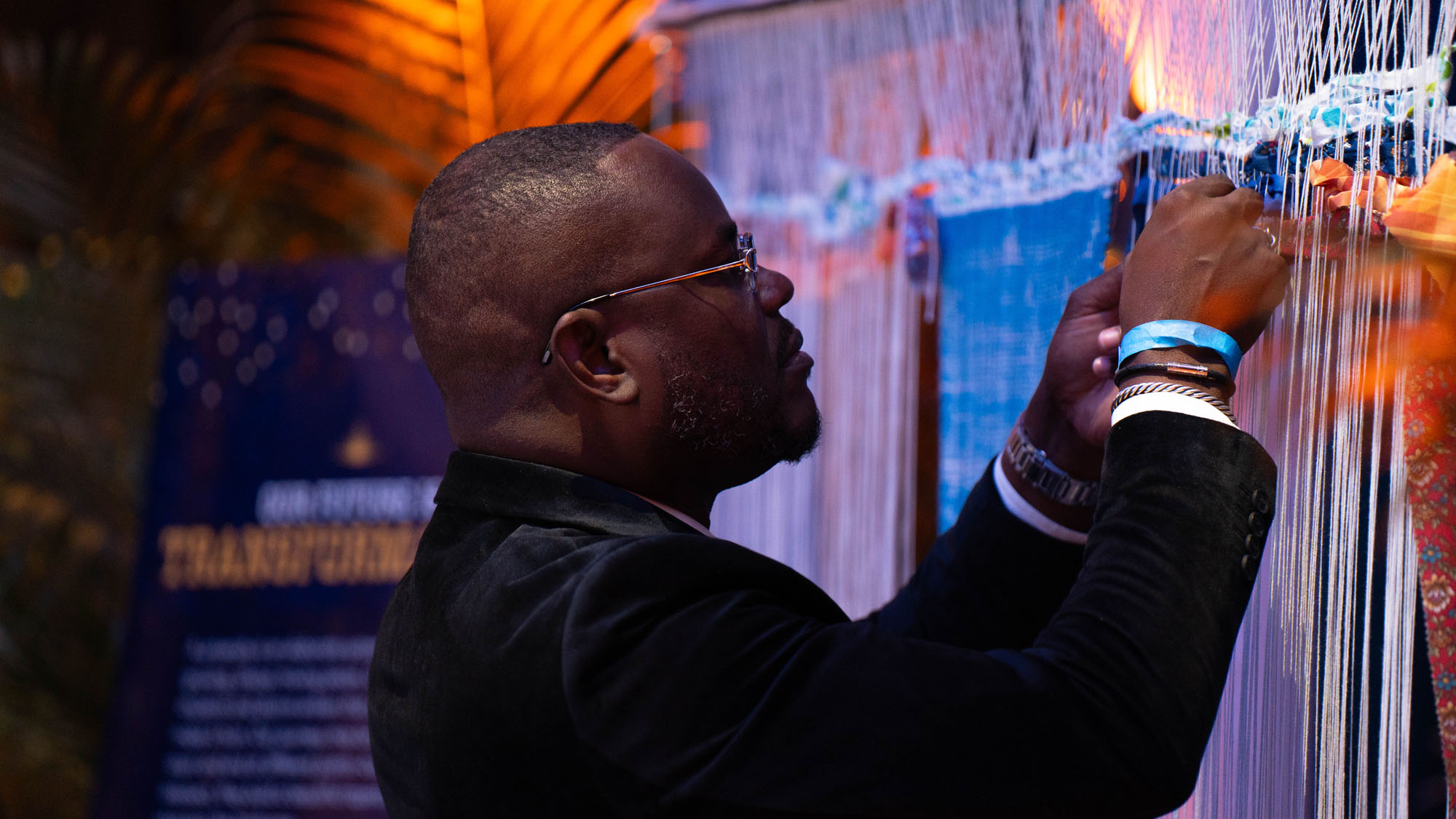 An individual adds a strand to a tapestry, one of the exhibits at the Centennial. 