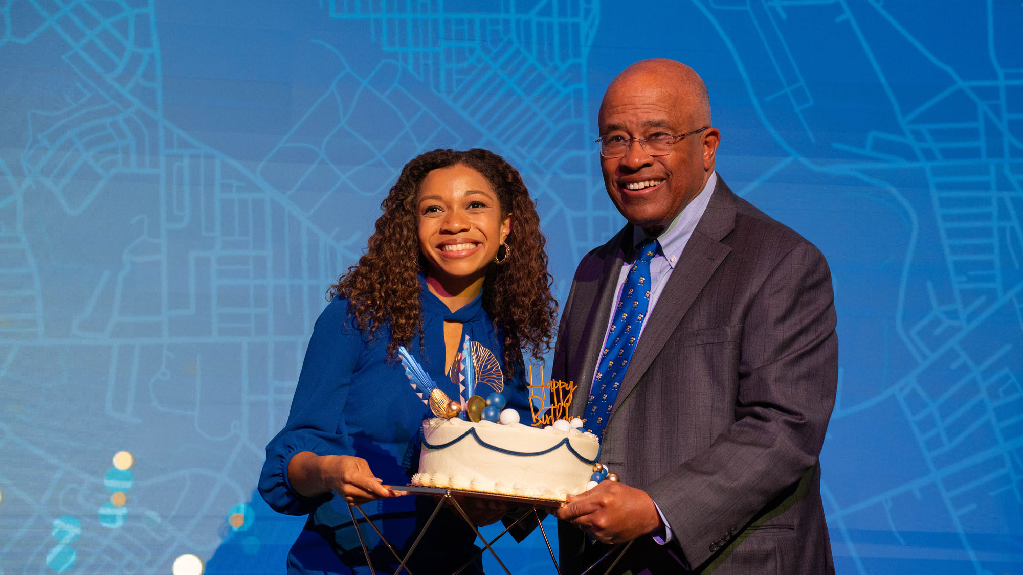 Breana Ross, a reporter from WBAL, poses with President Schmoke and the cake honoring UBalt's birthday.&nbsp;