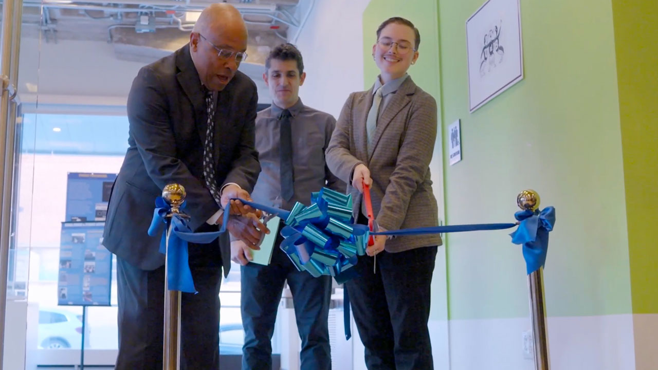 Kurt Schmoke and Lexzander Ernst cut a blue ribbon to open the Centennial exhibit while Dr. Josh Davis looks on. 