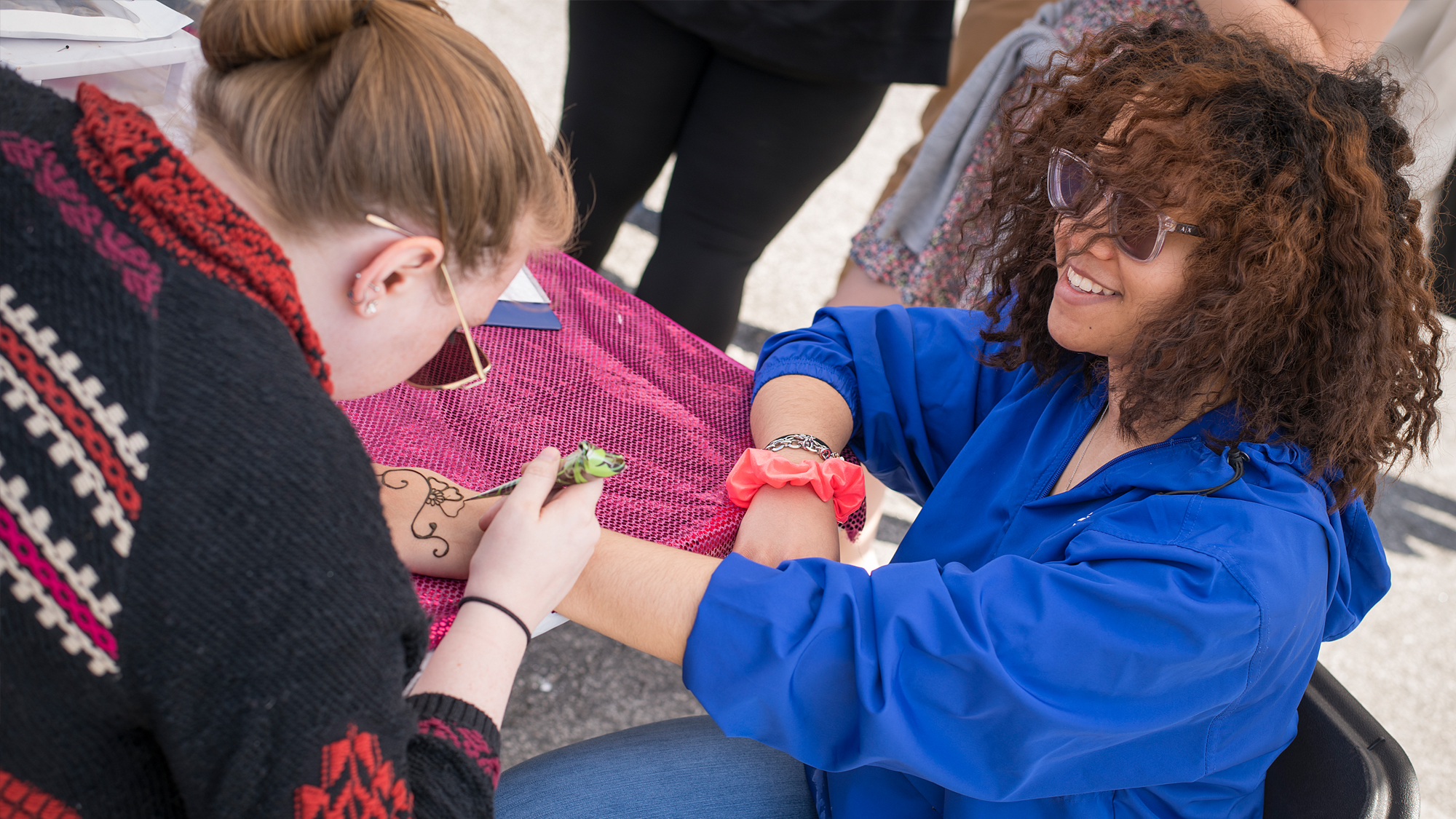 A student smiles while receiving a henna tatoo.