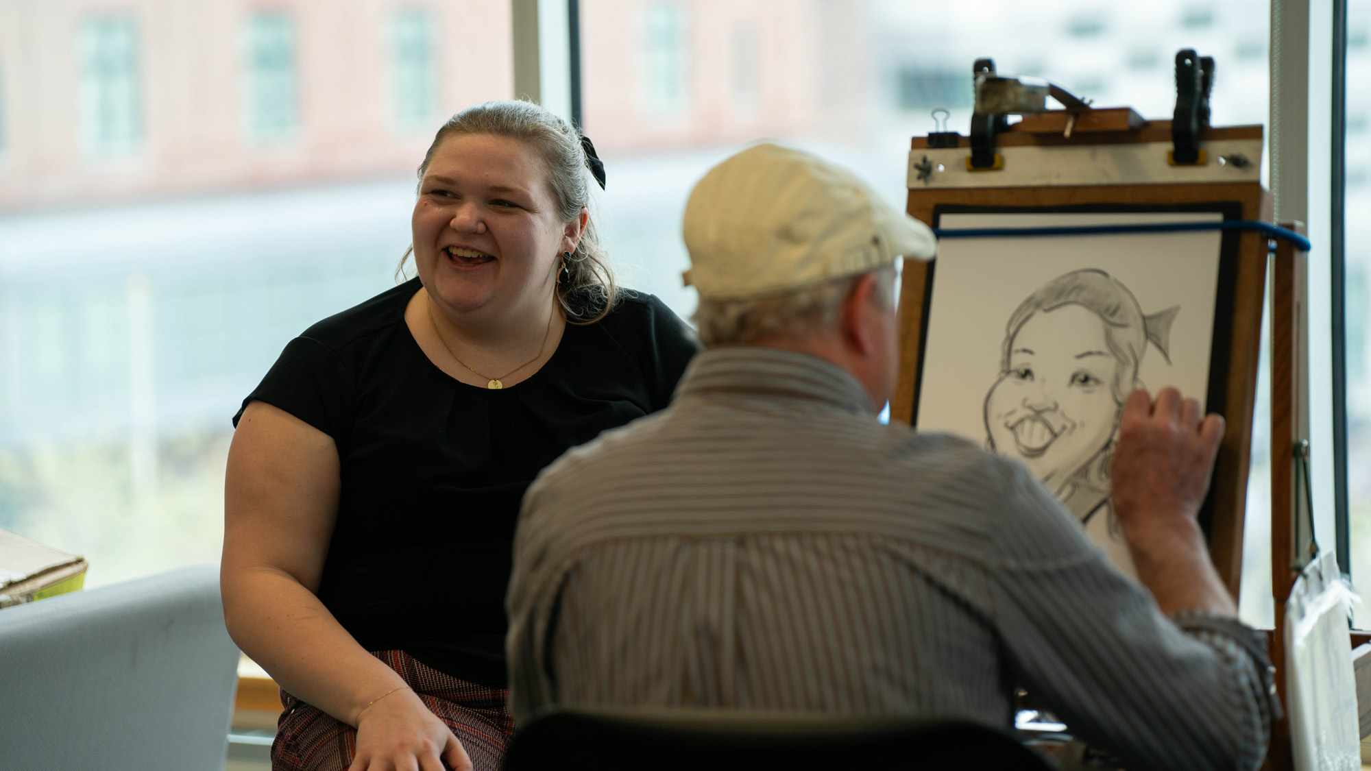 A student laughs while having their caricature down. 