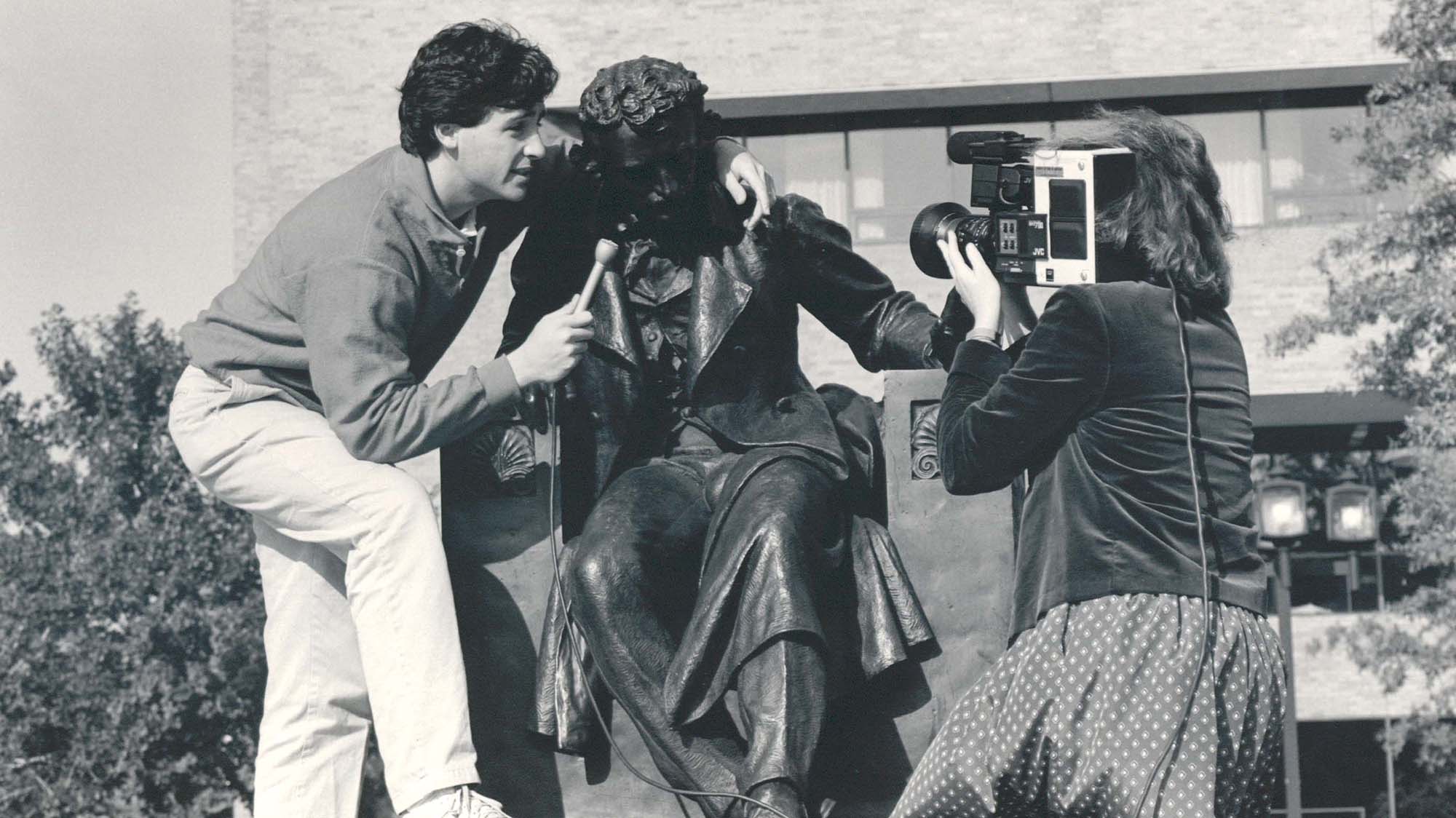 A news crew interviews the Edgar Allen Poe statue