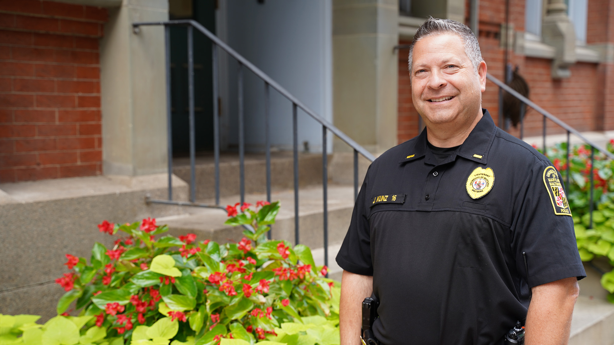 Jason Kunz poses in his police uniform on a city neighborhood street